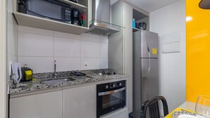 Eine kompakte Küche mit Einbauofen, Mikrowelle und Kühlschrank.