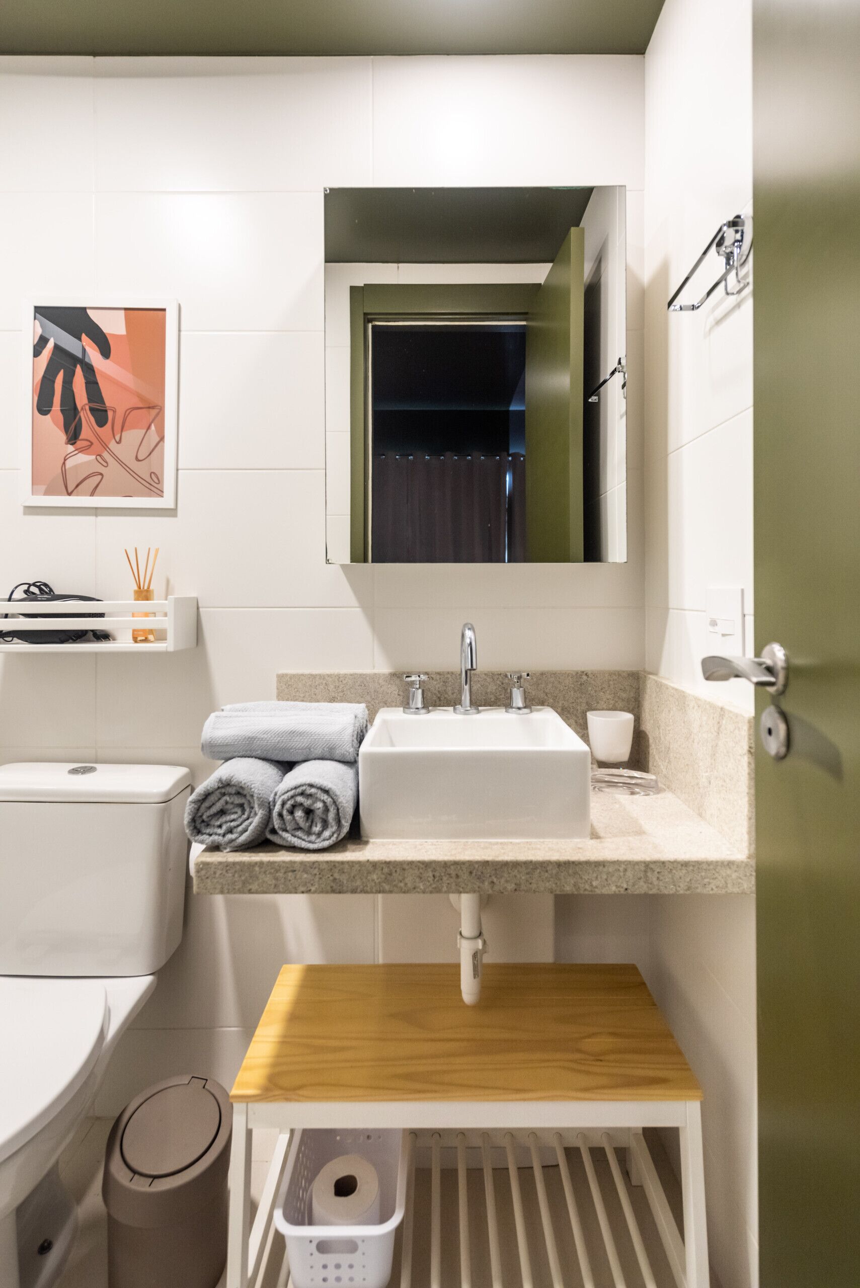 Ein modernes Badezimmer mit einem weißen Waschbecken, einer Holz-Kommode und einem Handtuchhalter.
