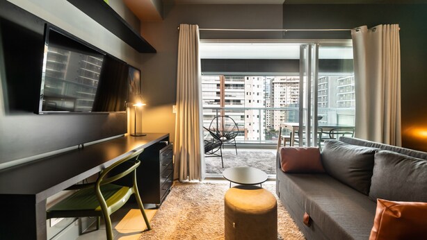 A modern living room with a sofa, ottoman, and a flat-screen TV mounted on the wall. - Vision0707 in S o Paulo (São Paulo)