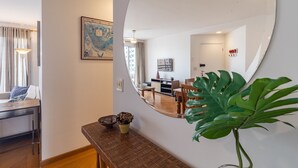 A modern living room with a large mirror, a dining area with a wooden table, and a potted plant. - Ia71 Apto 3 Quartos Itaim 4p 3q (São Paulo)