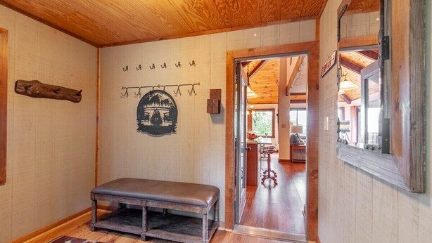 A wooden interior with a bench, a wall-mounted rack, and a door leading to another room.