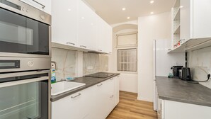 Une cuisine moderne avec des meubles blancs, un four double, un pare-feu en marbre et un plancher en bois.