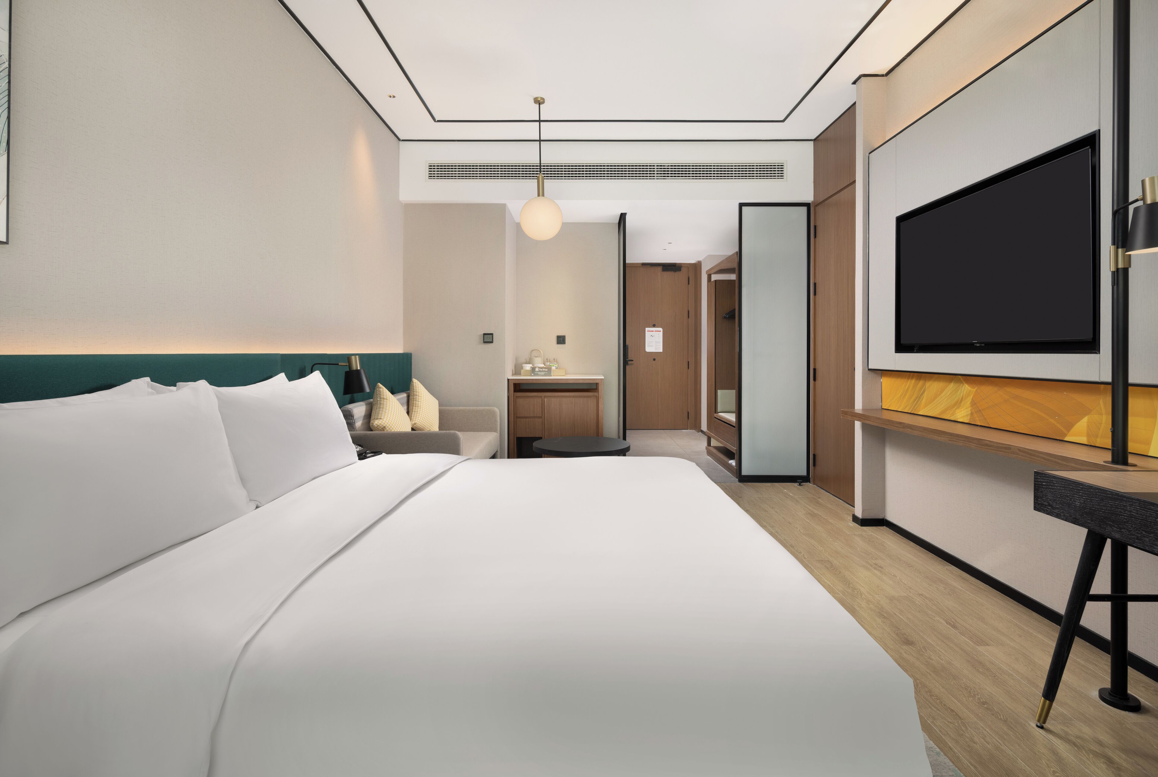 Een moderne hotelkamer met een groot bed, een bureau, een flatscreen-tv en een badkamer die door een open deur zichtbaar is.