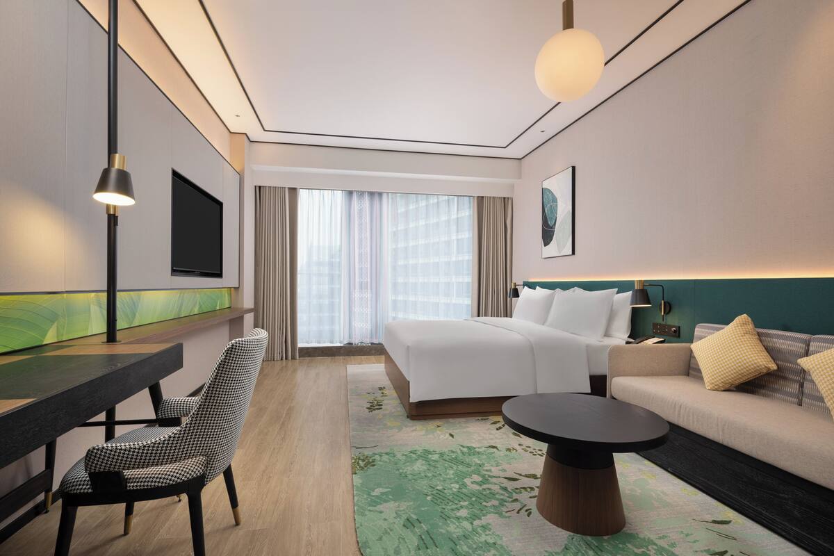 Ein Hotelzimmer mit Bett, Sofa, Schreibtisch und Fernseher.