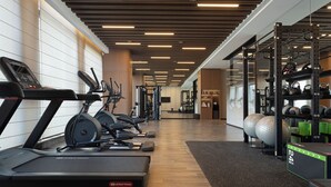 Une salle de sport moderne équipée de tapis de course, de vélos elliptiques et de matériel de musculation.