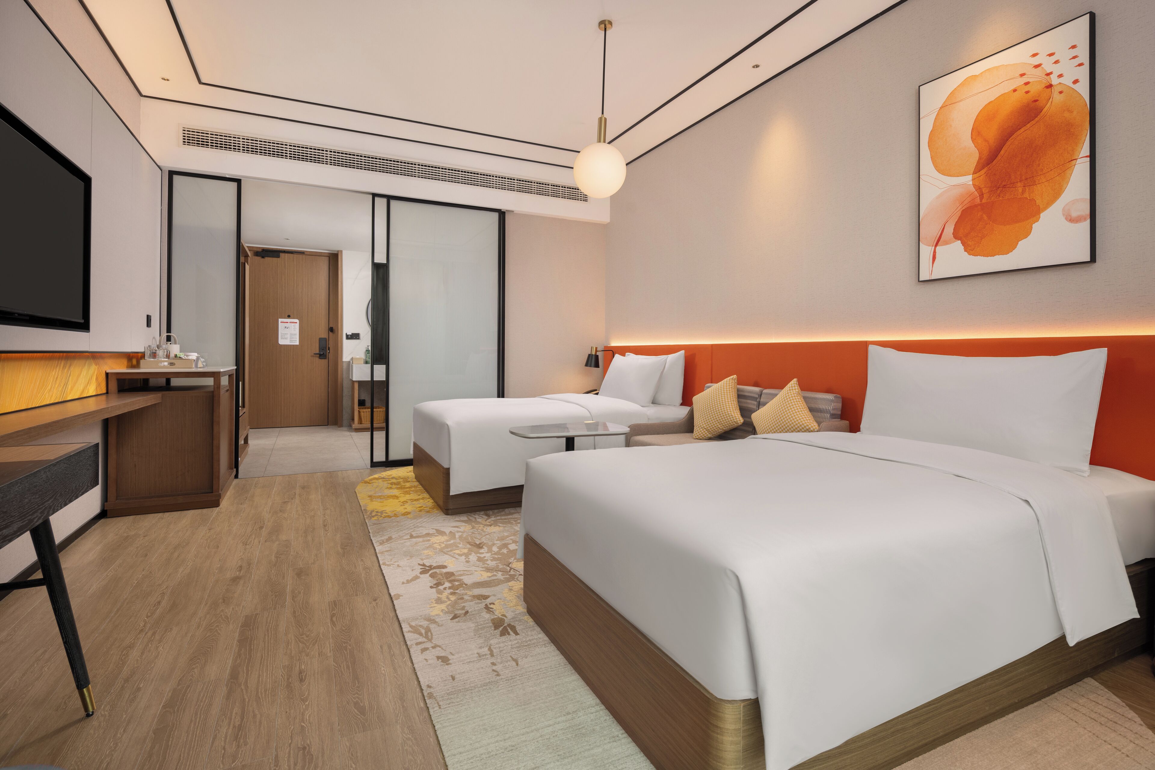 A modern hotel room with a large bed, a desk, and a TV.