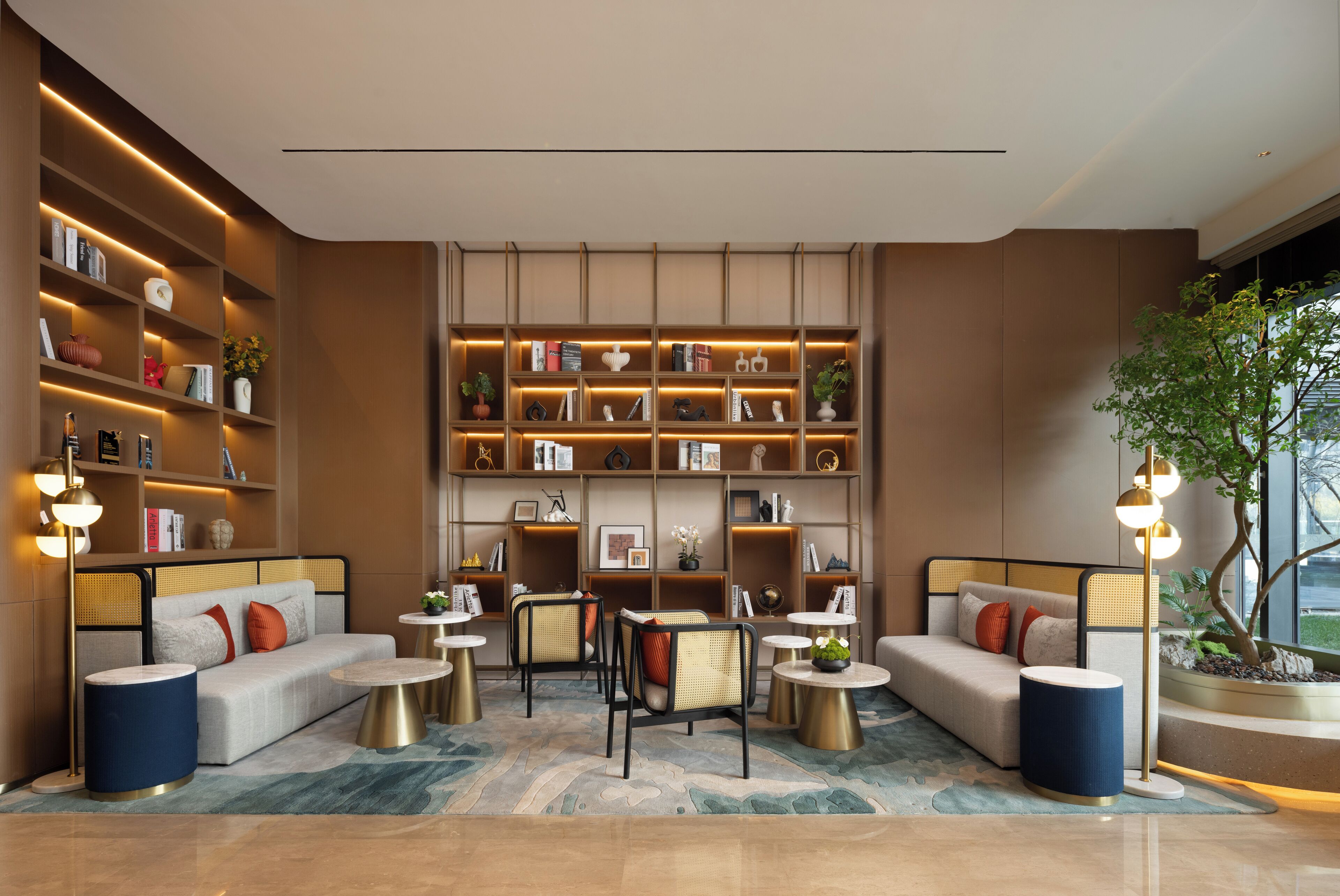 Un espace de détente moderne comprenant un canapé, des fauteuils, une bibliothèque et une plante en pot.