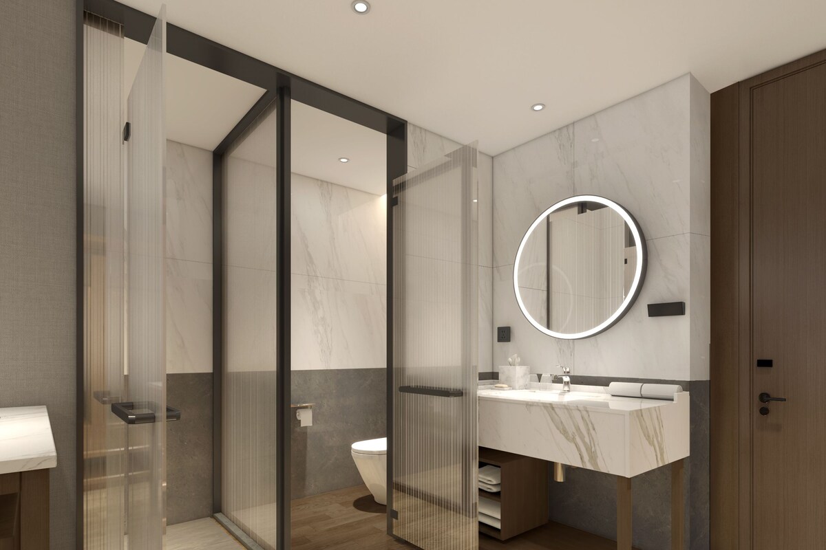 Un baño moderno con cabina de ducha de vidrio, lavamanos de mármol y suelo de madera.