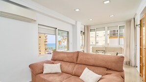 A modern living room with a sofa, a dining table, and large windows offering a view of the sea. - Apartment 'Playa Algarrobo Costa' with Sea Views, Wi-Fi and Air Conditioning (Algarrobo-Costa)