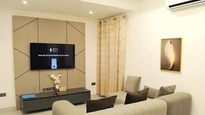 Ein modernes Wohnzimmer mit Flachbildfernseher an der Wand, einer Couch, einem Konsolentisch und einem dekorativen Federbild.