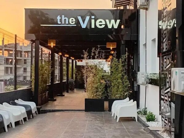 An outdoor seating area with white plastic chairs and a black awning with the text "the View".