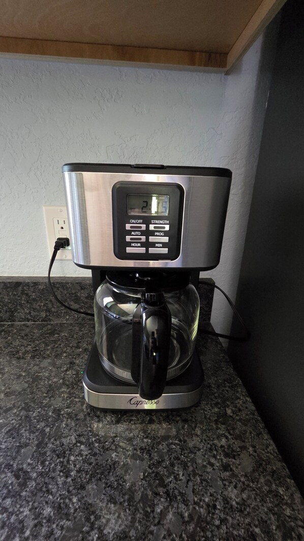 A coffee maker with a digital display, a power cord, and a brand name on the base.