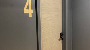A door with a number '4' on the wall, a light switch, and a wooden floor.