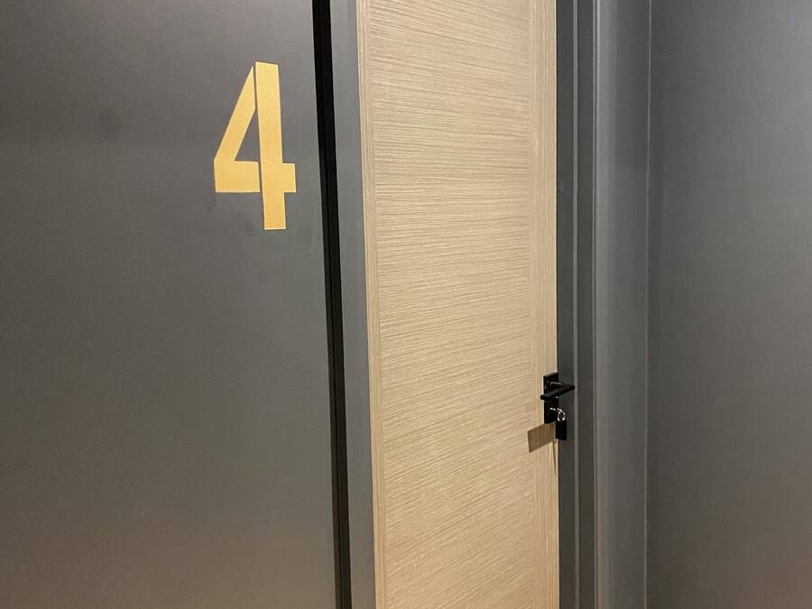 A door with a number '4' on the wall, a light switch, and a wooden floor.