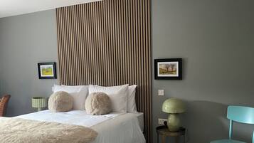 A modern bedroom with a large bed, a striped headboard, a small side table with a lamp, and a chair.