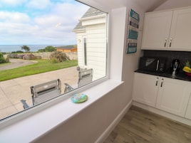 Una cocina con vistas al mar, un pequeño comedor con sillas y un armario con un letrero.
