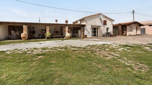 Ein Wohnhaus mit überdachter Terrasse, Sitzgelegenheit im Freien und einem Schotterweg.