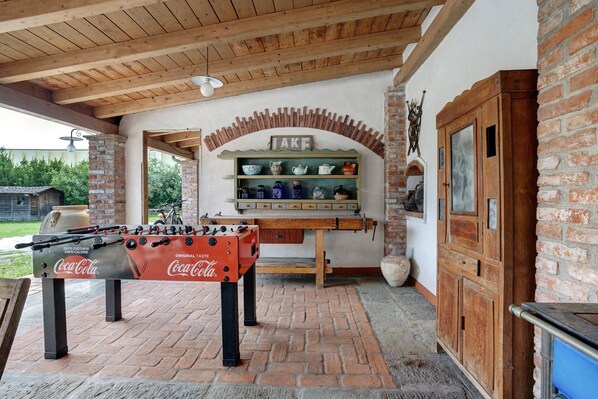 A foosball table, a coffee machine, and a brick wall with a sign above it.