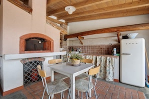 A kitchen with a brick oven, a refrigerator, and a dining table with chairs.