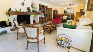 Un salon chaleureux avec une cheminée, des meubles en bois, un fauteuil rouge et un canapé blanc.