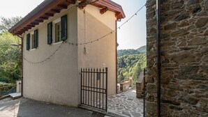 Un edificio de piedra con un acceso de baldosas, una reja metálica y una guirnalda de luces.