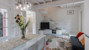 Una sala de estar moderna con una mesa de comedor de vidrio, un sofá, un televisor y una escalera.