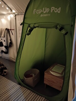 Uma tenda verde com a inscrição 'Pop-Up Pod', contendo uma pequena caixa de madeira e uma sacola.