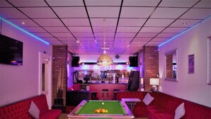 A billiards room with a pool table, red sofas, a bar area, and a chandelier. - MyRoomz Silver Strand Hotel (Blackpool)