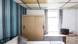 A hotel room with a bed, a desk with a television, and a window with curtains. - MyRoomz Silver Strand Hotel (Blackpool)