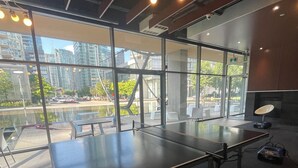 A ping pong table in a modern indoor space with large windows and a view of a cityscape. - 2-bdr 1 bath downtown  luxury condo, free parking sleeps 6 (Toronto)