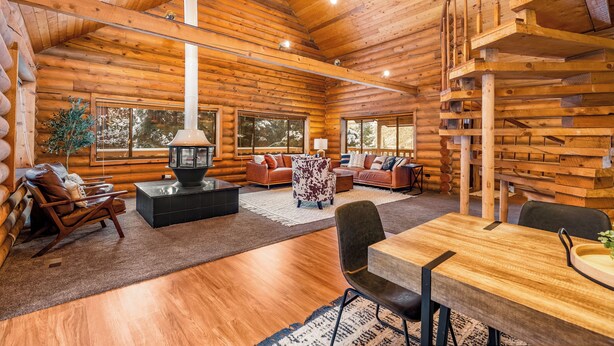 A log cabin interior with a fireplace, wooden floors, and a staircase. - Lodge at Summit Park Near Woodward (Park City)