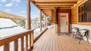 A wooden deck with a railing, a door, and two wicker chairs. - Lodge at Summit Park Near Woodward (Park City)