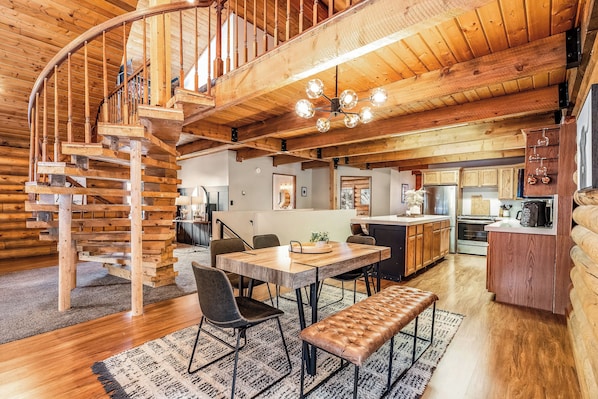 A wooden interior with a spiral staircase, a dining area with a bench, and a kitchen with wooden cabinets.