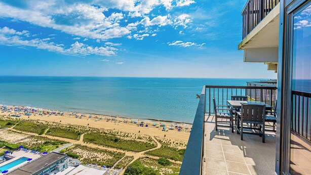 A balcony with a view of the beach and ocean, a pool, and outdoor seating. - Sea Watch- Penthouse, Oceanfront 4 BR, two floors (Ocean City)