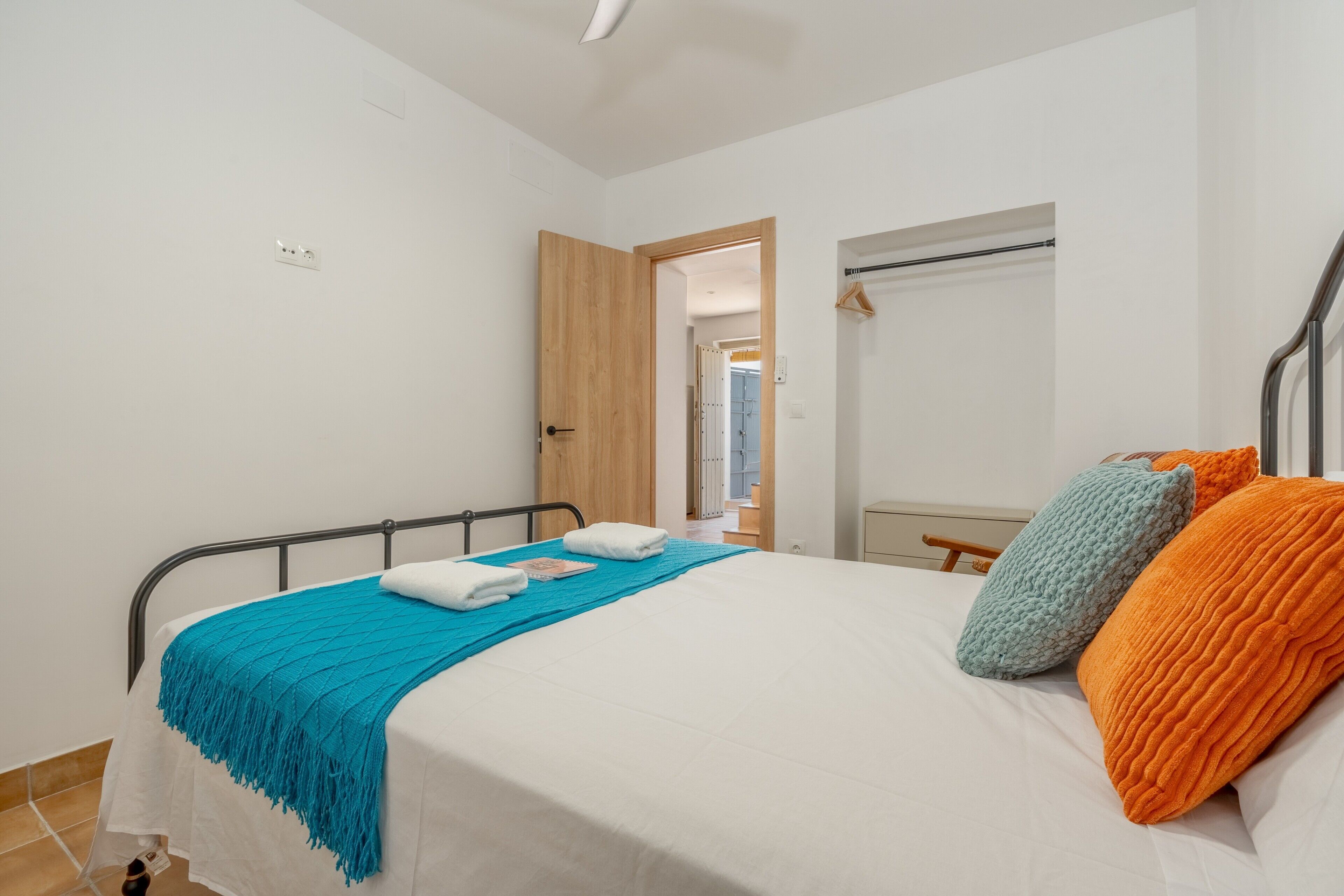 A bedroom with a bed, a wooden door, a mirror, and a window.