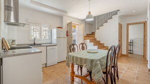 A modern kitchen with white cabinets, a stainless steel range hood, and a dining area with a table and chairs. - Casa Mercedes for Large Families. Air Conditioning (Valderrubio)