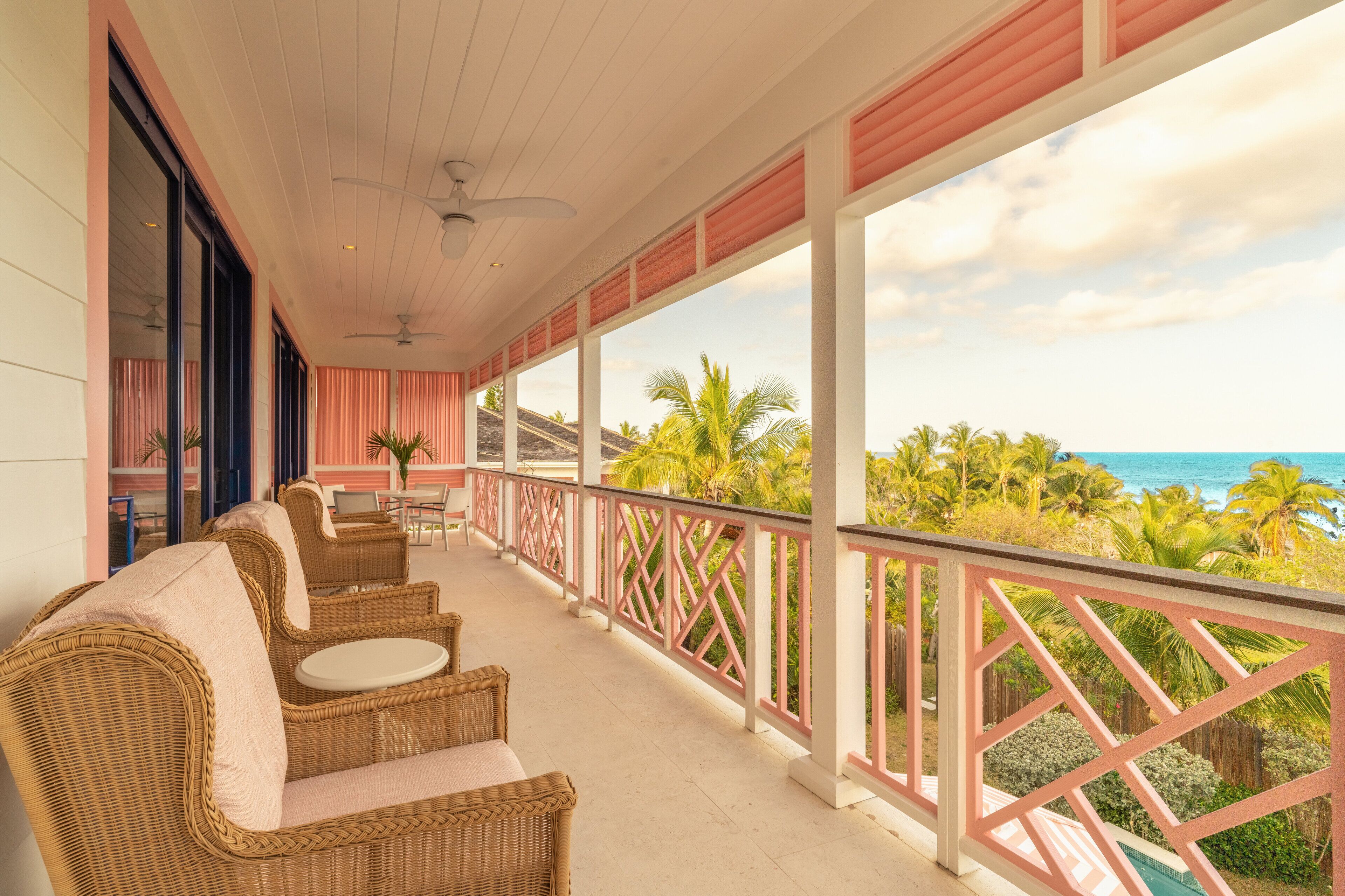 A covered outdoor area with wicker furniture and a view of the ocean.