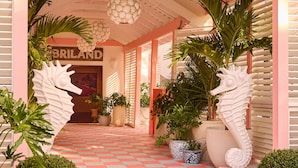 A hotel entrance with a pink facade, a tiled floor, and large potted plants. - Private Pool Villa at Coral Sands Steps to Pink Sand Beach & Resort Amenities (Dunmore Town)