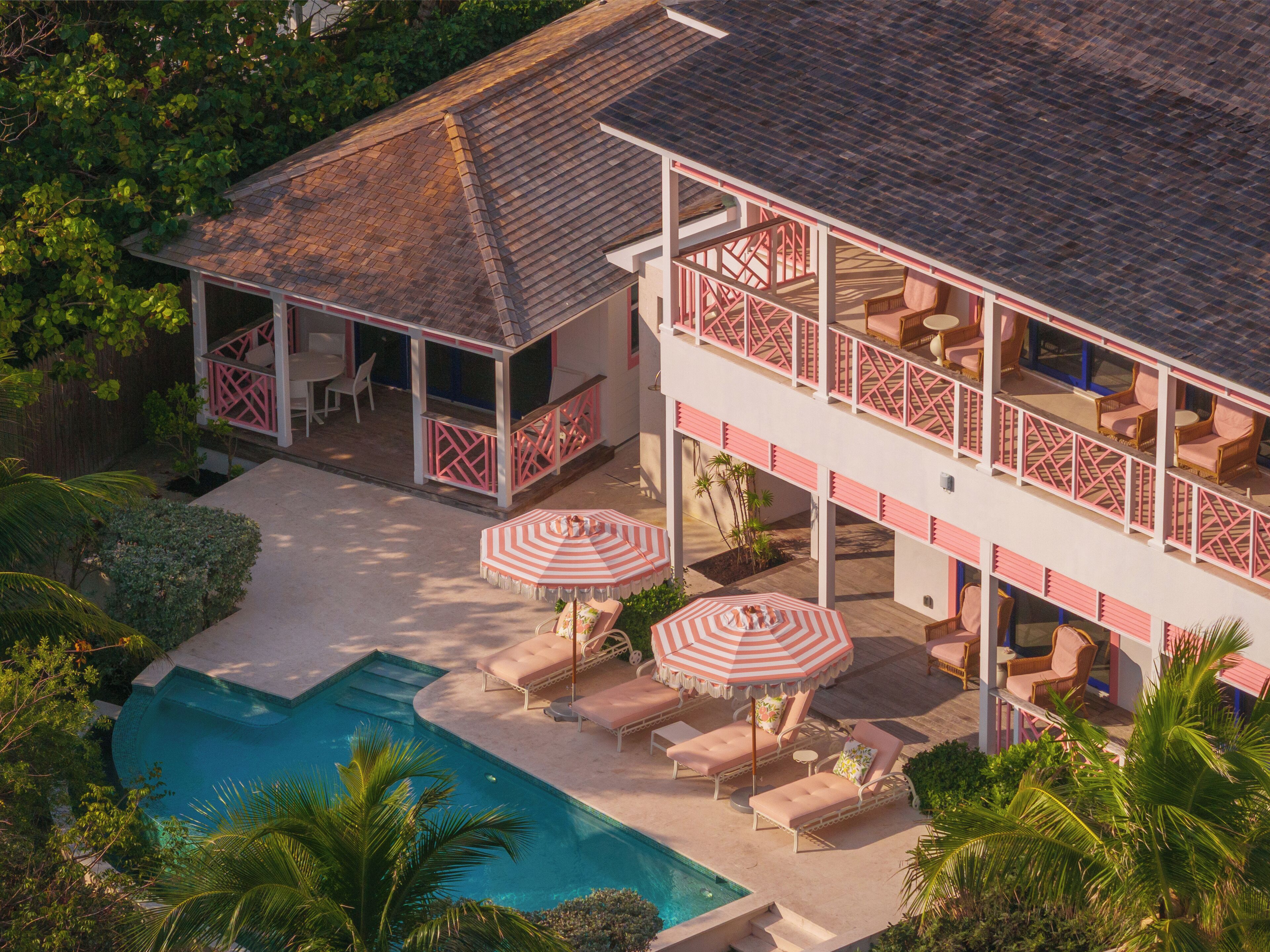 A two-story building with a pool, outdoor seating, and a covered patio area.