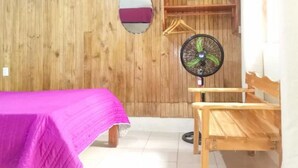 A room with a bed, a wooden bench, a fan, and a mirror on the wall. - Casita happy feet and tours corcovado - Family Room with Garden View (Bahía Drake)