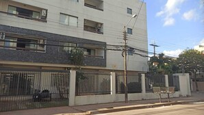 A multi-story building with a modern facade, a gated entrance, and a visible balcony.