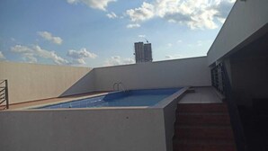 A rooftop swimming pool with a view of a tall building in the background.