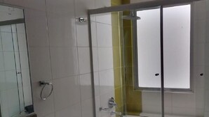 A bathroom with a glass shower enclosure, a white toilet, and a sink with a granite countertop.