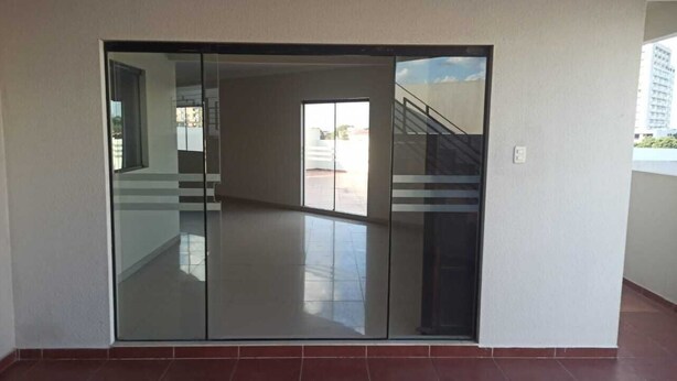 A room with a sliding glass door leading to a balcony with a view of a building and a staircase.