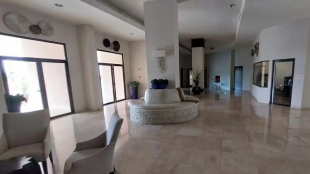 Un vestíbulo amplio con una zona de estar central, ventanas grandes y un diseño moderno.
