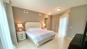 Un dormitorio con cama, mesitas de noche, escritorio y silla.