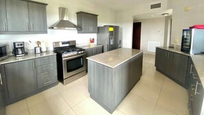 Una cocina moderna con armarios grises, una isla central, estufa y refrigerador.