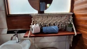 A bathroom with a wooden vanity, a sink, and a macrame shelf with toiletries. - Casita happy feet and tours corcovado - bedroom #6 (Drake Bay)