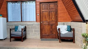 A room with a wooden door, a white refrigerator, and two wooden chairs with cushions. - Casita happy feet and tours corcovado - bedroom #6 (Drake Bay)