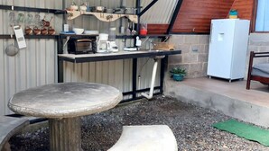 A rustic outdoor kitchen with a stone table, a built-in oven, and various cooking utensils. - Casita happy feet and tours corcovado - bedroom #6 (Drake Bay)